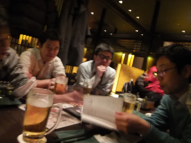 二次会の飲み会の席で本を開いて語り合う参加者たち