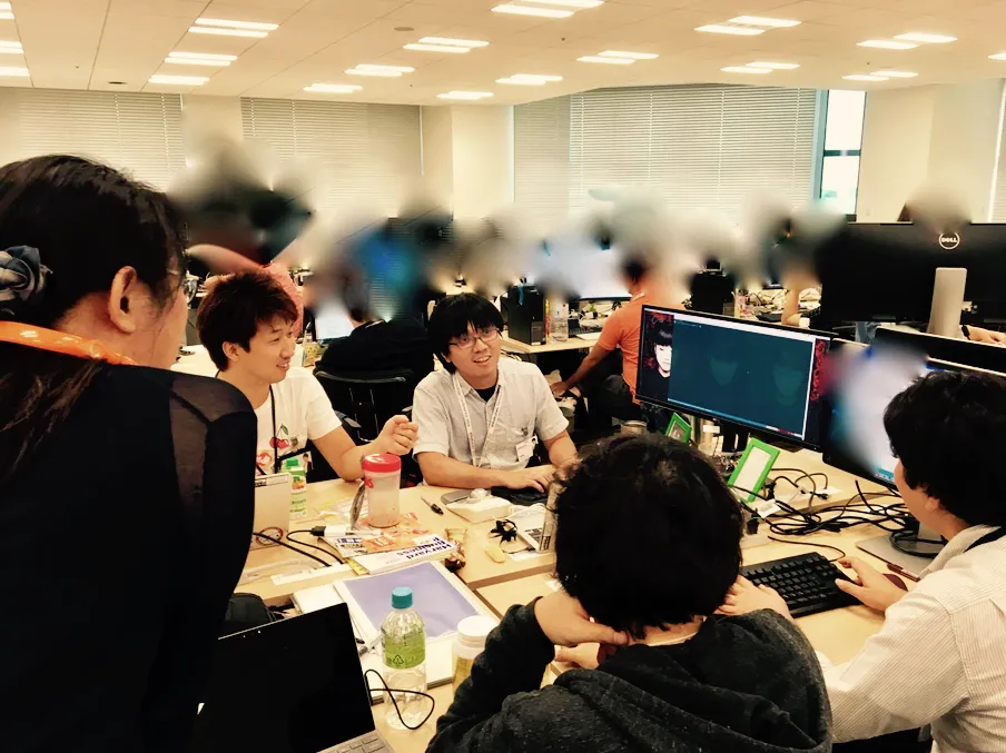 オフィスでメンバーが集まって議論しながら開発している様子