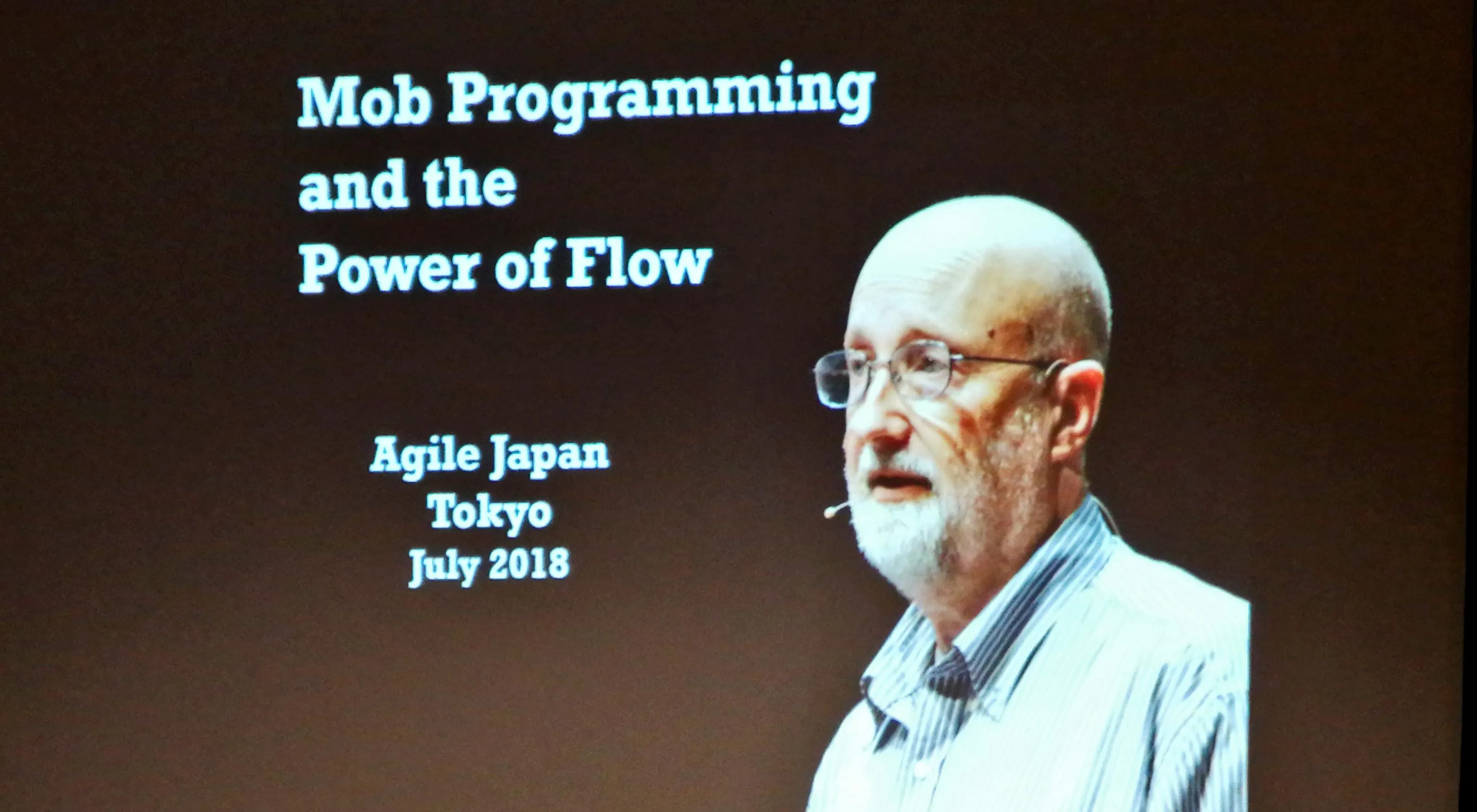 「Mob Programming and the Power of Flow」のタイトルスライドと講演するWoody氏