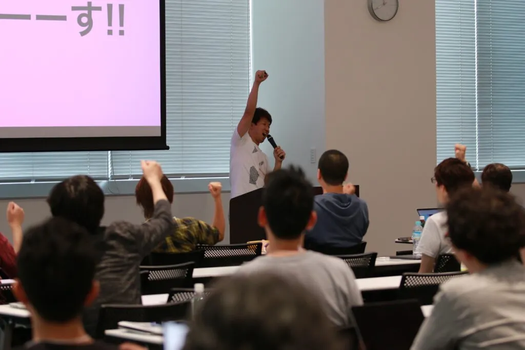 会場の参加者と一緒に拳を上げて登壇を締めくくる様子